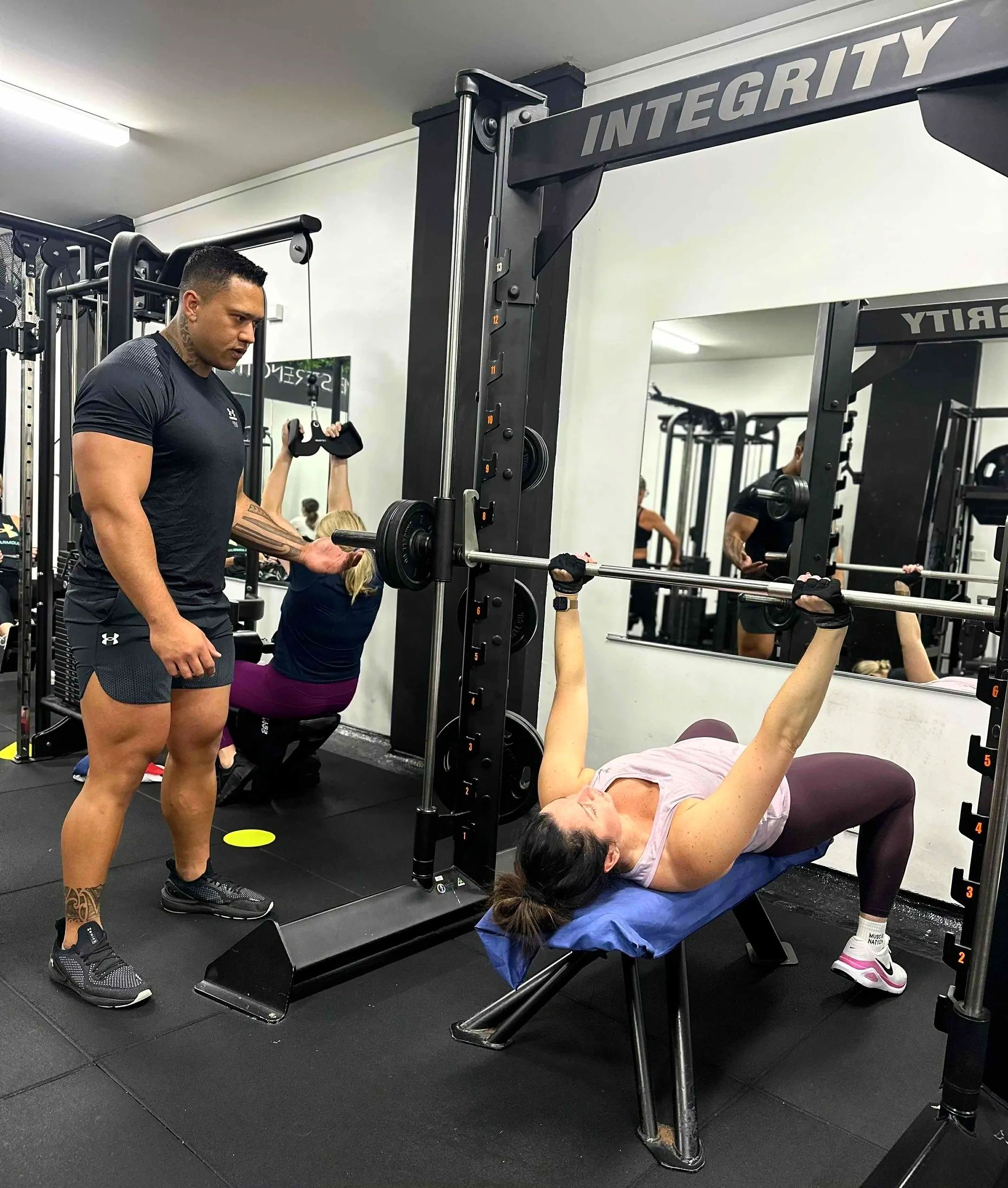 Mak coaching a member through a bench press
